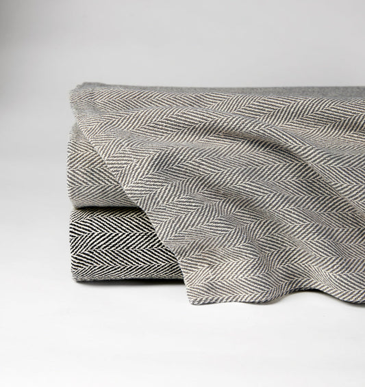 The SFERRA Celine herringbone blanket woven in soft colors with cream.