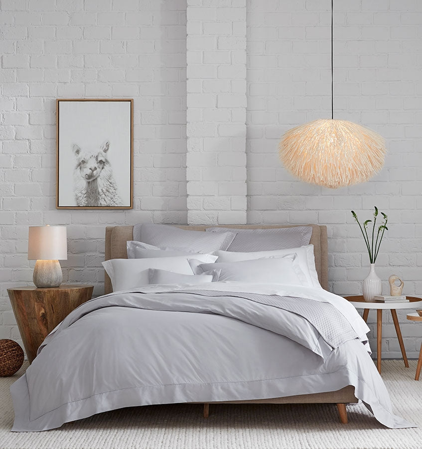 A bed with SFERRA Celeste percale bedding, woven in Italy from pure, extra-long-staple cotton for a super soft hand.