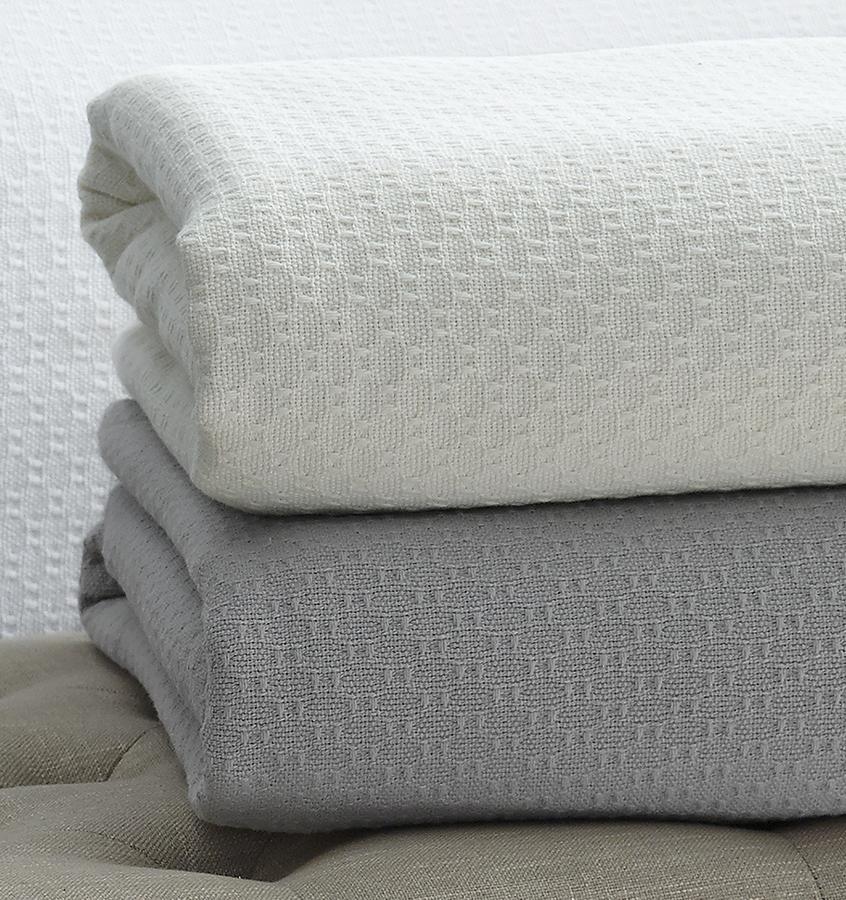 The SFERRA Corino lightweight, breathable cotton blanket in white, ivory, seagreen, and powder blue.