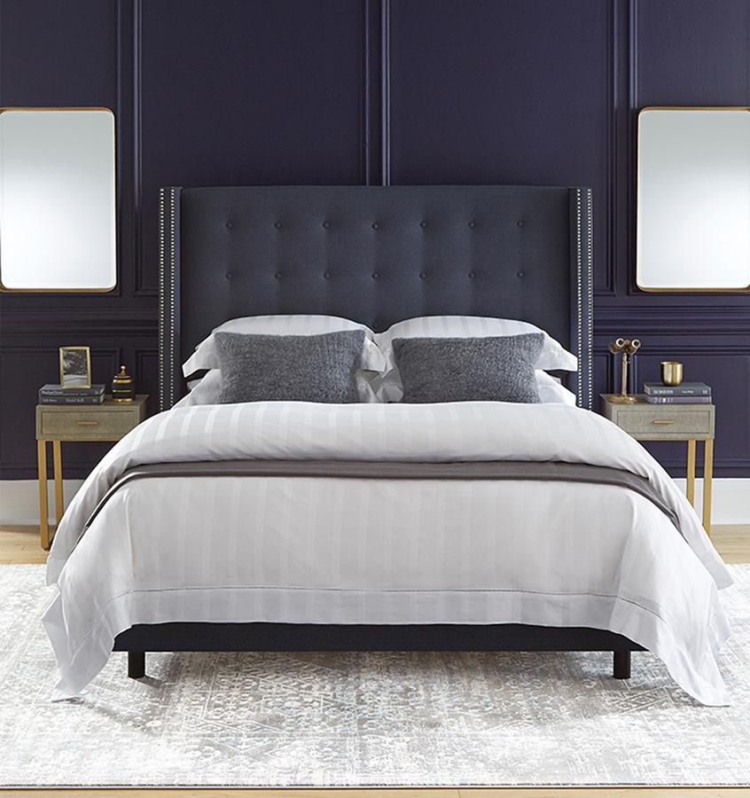 A bed with SFERRa Giza 45 Stripe bedding, crafted from the finest cotton in the world.