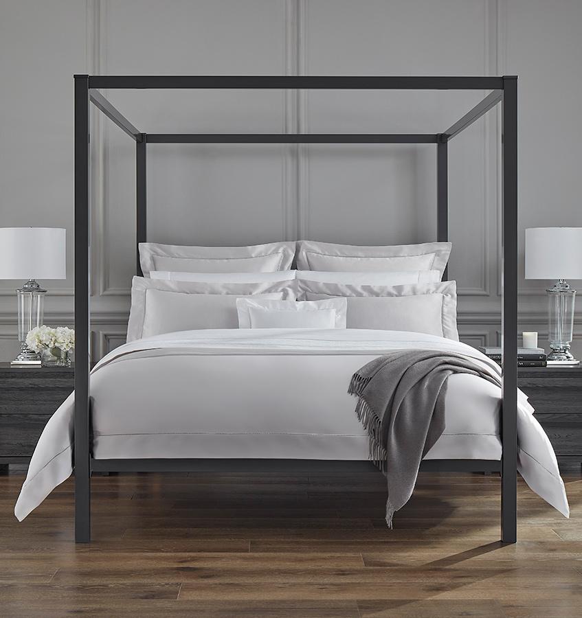 An all-white bed with SFERRA Giza 45 Sateen bedding, grown in the Nile river valley, woven by master craftsmen in Italy, and made of the finest cotton in the world